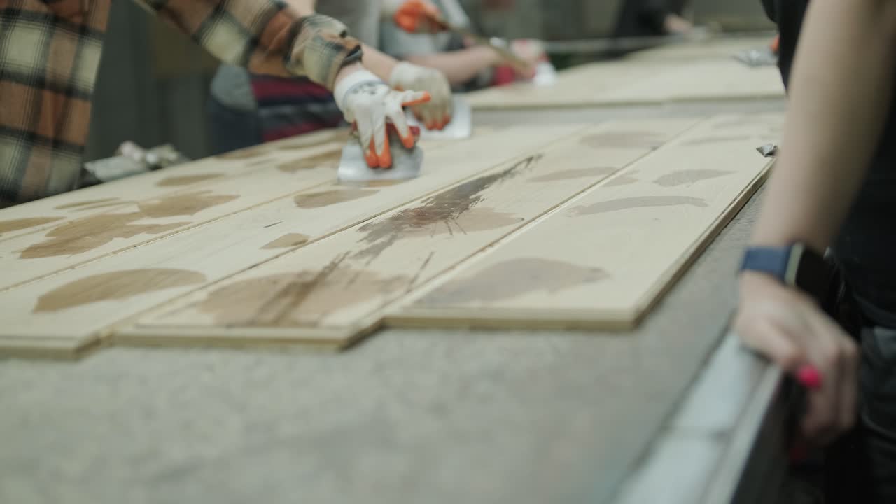Operai che applicano un rivestimento su tavole di legno in una fabbrica.