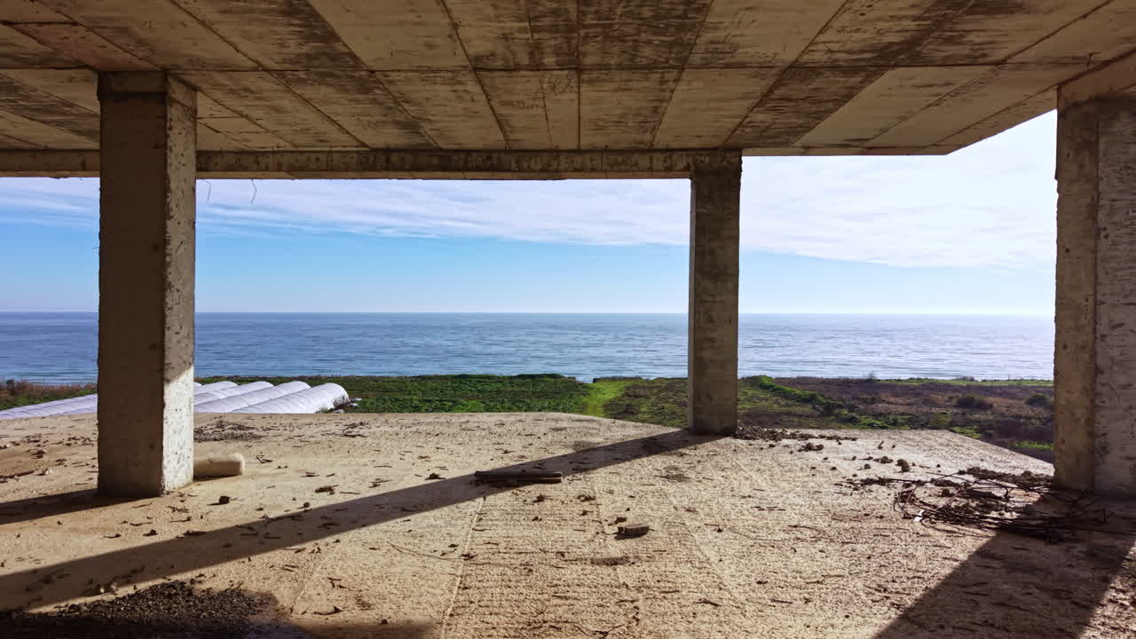 Vista de ondas oceânicas tranquilas através de uma estrutura costeira com pilares de concreto sob um céu claro