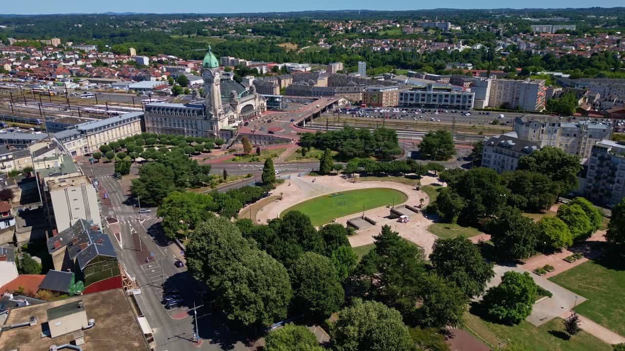 Aerial pullback shot showing Limoges train station and the Champ de Juillet park on a sunny day - France