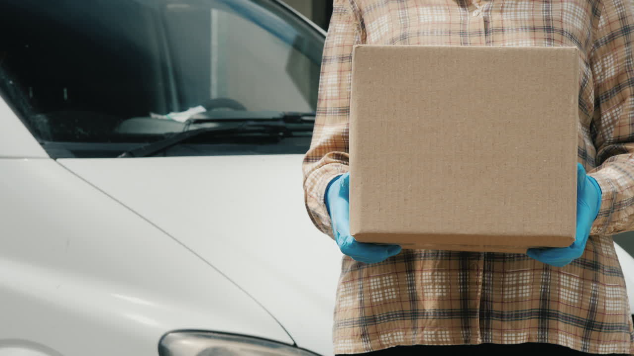 un trabajador del servicio de entrega sostiene un paquete cerca de una camioneta