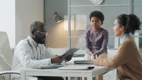 african american pediatrician speaking with woman and child on consultation