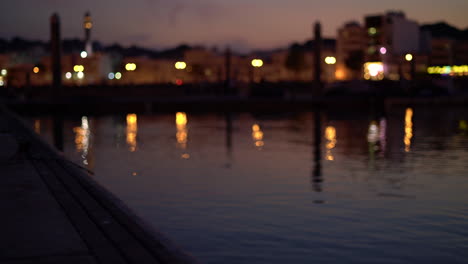 dock with water ripples reflection of lights and city in muttrah, oman