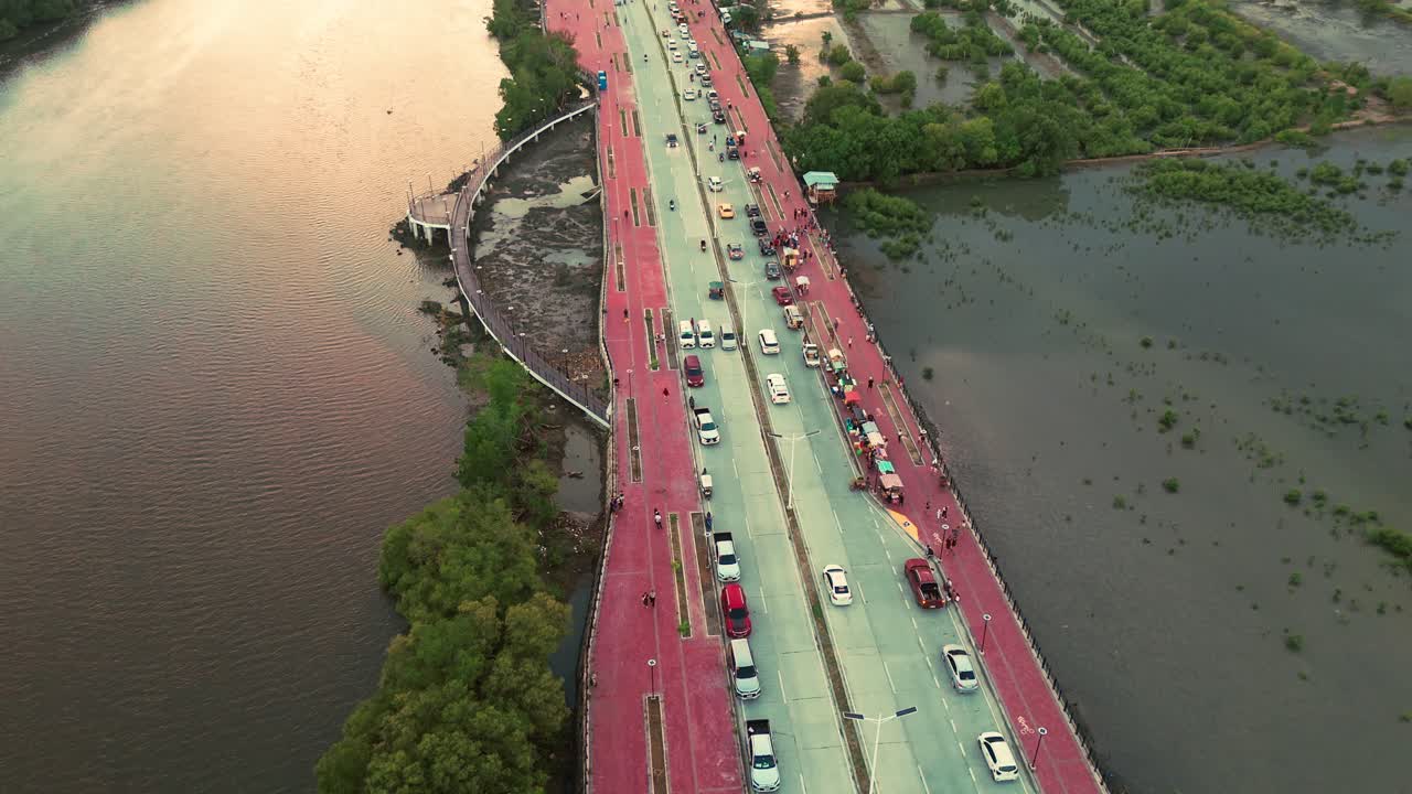 A wide aerial view showing a bridge with traffic, surrounded by water and greenery. Ideal for showcasing urban landscapes, infrastructure, and scenic transportation routes