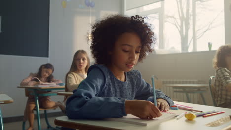 Mädchen-Sitzt-Am-Schreibtisch-Im-Klassenzimmer.-Fröhlicher-Student,-Der-In-Ein-Notizbuch-Schreibt