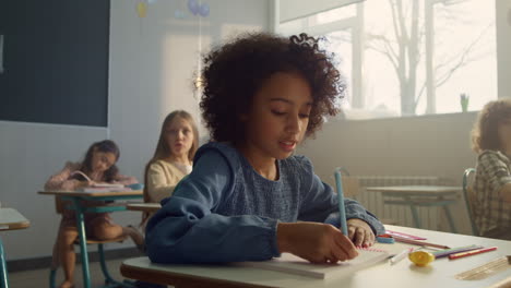 chica sentada en el escritorio en el aula. estudiante alegre escribiendo en el cuaderno