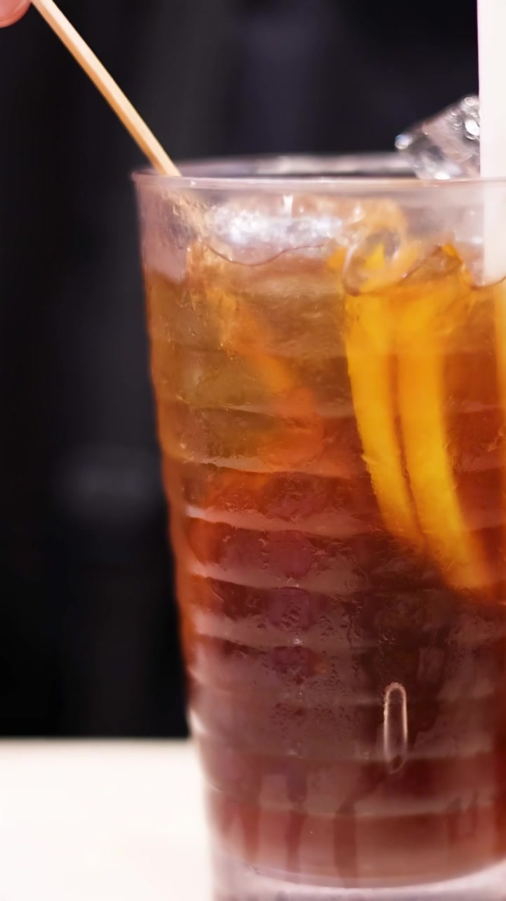 Mani che mescolano tè freddo con fette di limone