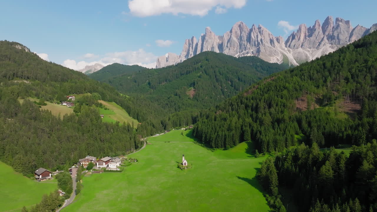Scenic drone establishing of Church of St. John in a green valley of the Dolomites, Italy
