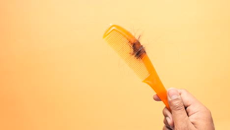 hand holding orange comb with hair