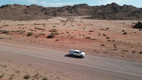 un elegante toyota hilux blanco se desliza a través del paisaje marciano de namibia, su robusta elegancia conquistando interminables carreteras polvorientas