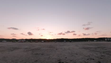 The-waves-from-the-Gulf-of-Mexico-break-onto-the-beach-in-Port-Aransas,-Texas-while-people-watch-the-sunset