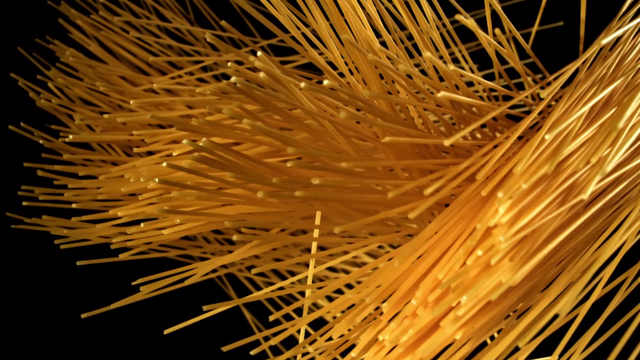 Spaghetti secchi che cadono al rallentatore su sfondo nero