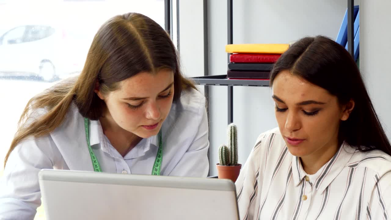 dos jóvenes mujeres de negocios trabajando juntas en una computadora
