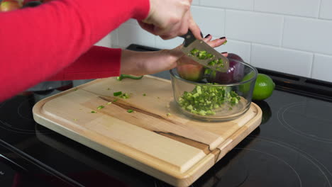 mujer sacando jalapeños recién picados en un recipiente de vidrio