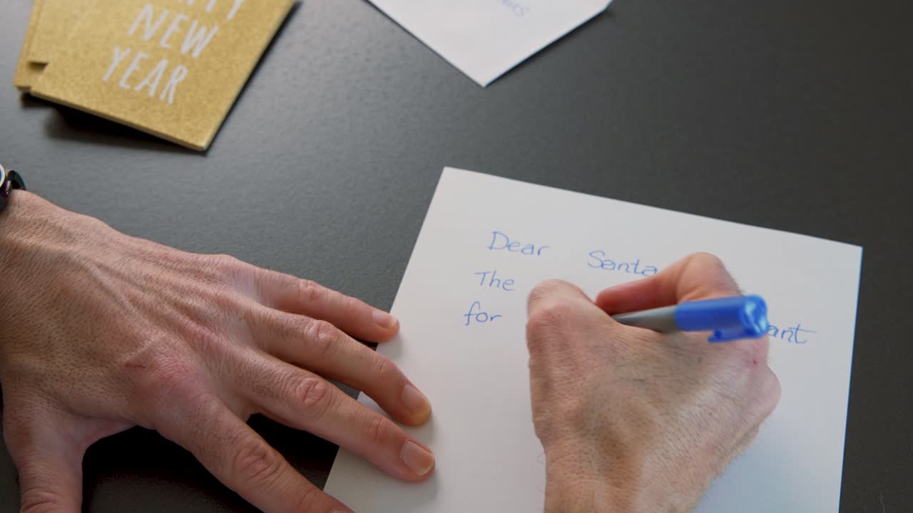 Writing of Christmas wish letter to Santa Claus, envelopes on table