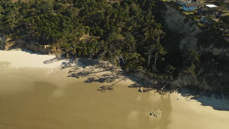 imagen de un dron retirándose de la playa para revelar el barrio del faro de yaquina head en newport, oregon