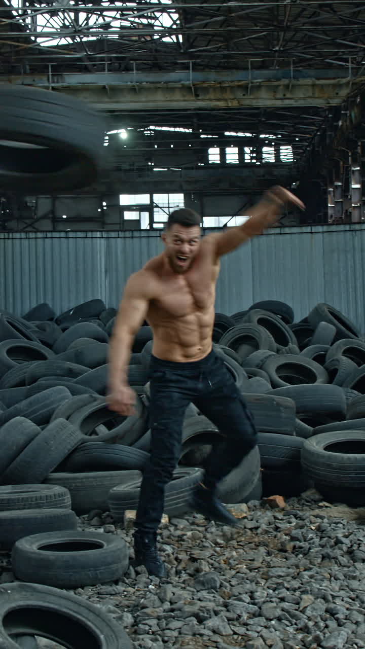 Muscular man throwing tire. Young muscular man working out with tire