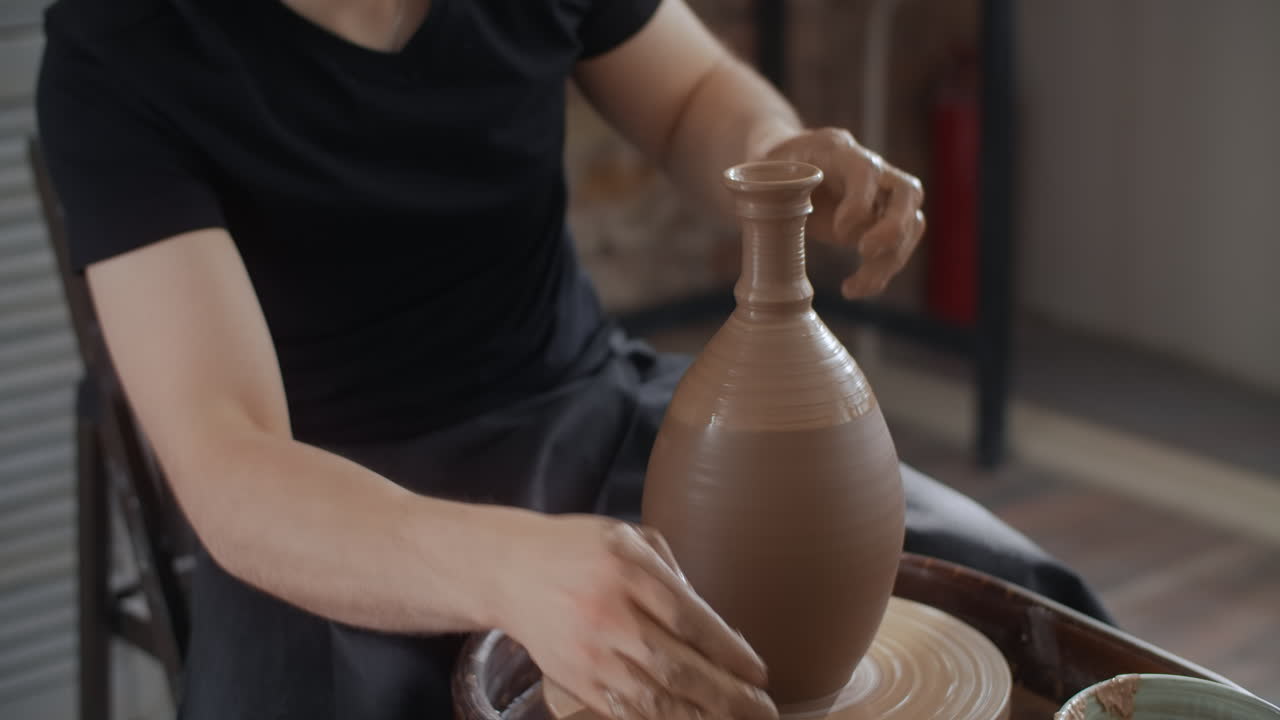 Potter shaping a vase on a pottery wheel