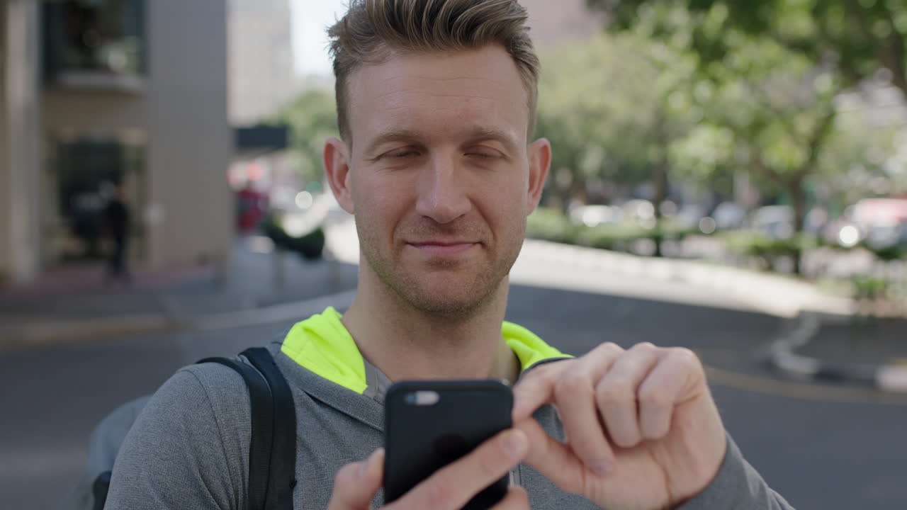 retrato de un joven guapo y alegre enviando mensajes de texto navegando usando mensajes de teléfono inteligente en la concurrida acera de la ciudad