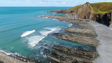 aerial shot of the waves in the sea at spekes mill coastal beach in devon on a sunny day