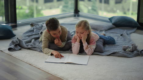 Niño-Niña-Acostada-En-La-Alfombra-Con-Un-Libro.-Hermanos-Buscando-Información-En-El-Libro-De-Texto