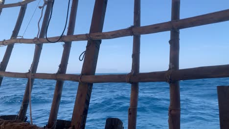 Las-Olas-Del-Mar-árabe-Están-Moviendo-El-Barco-Local-Con-Dificultad,-Y-Una-Montaña-Lejana-Aparece-En-El-Horizonte