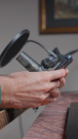 hands holding a smartphone in a recording studio setup