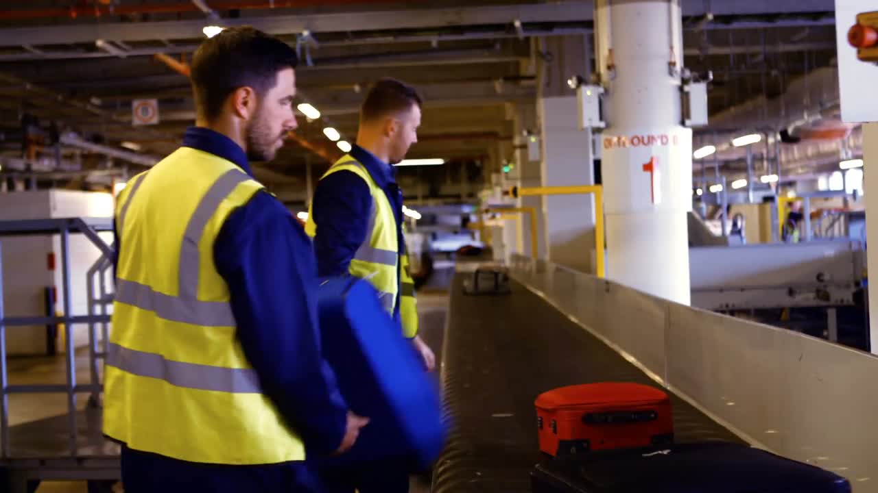 Two airport worker putting baggage on baggage carousel