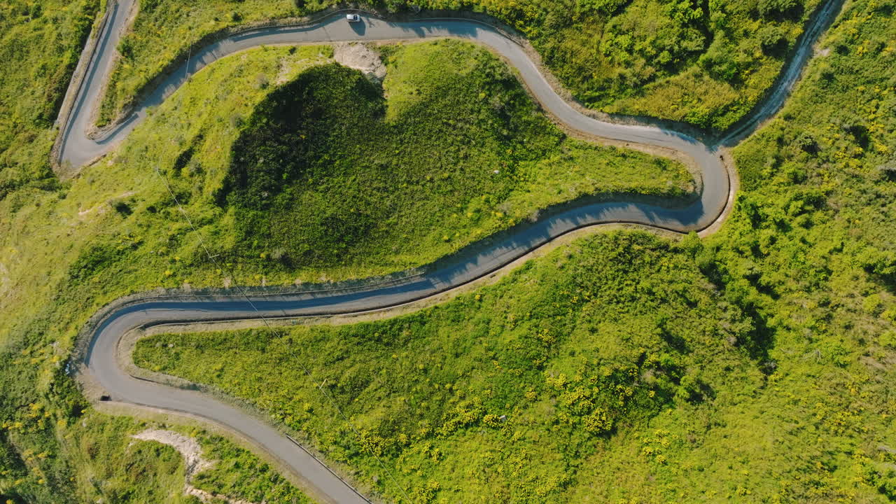 Strada stretta che si inerpica su una montagna con prati verdi in Calabria