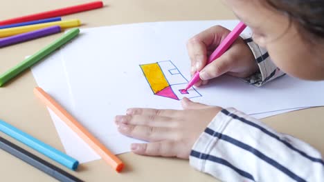 side view of little girl at her table drawing,