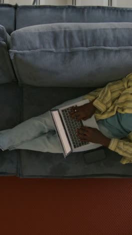 mujer relajándose en el sofá trabajando en la computadora portátil