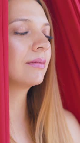 calm and relaxed lady sits with closed eyes in fly yoga hammock and relaxes after exercises extreme close view