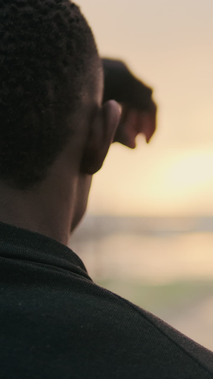 Man Looking Out at Golden Hour Sky with Hand Shading Eyes