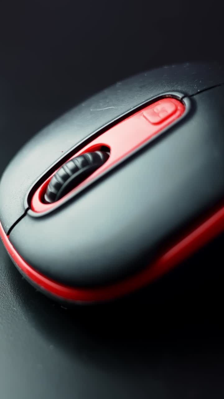 Extreme macro of a black and red computer mouse showing the textured scroll wheel and buttons in soft light—clean tech b-roll for productivity, gaming, and UI themes