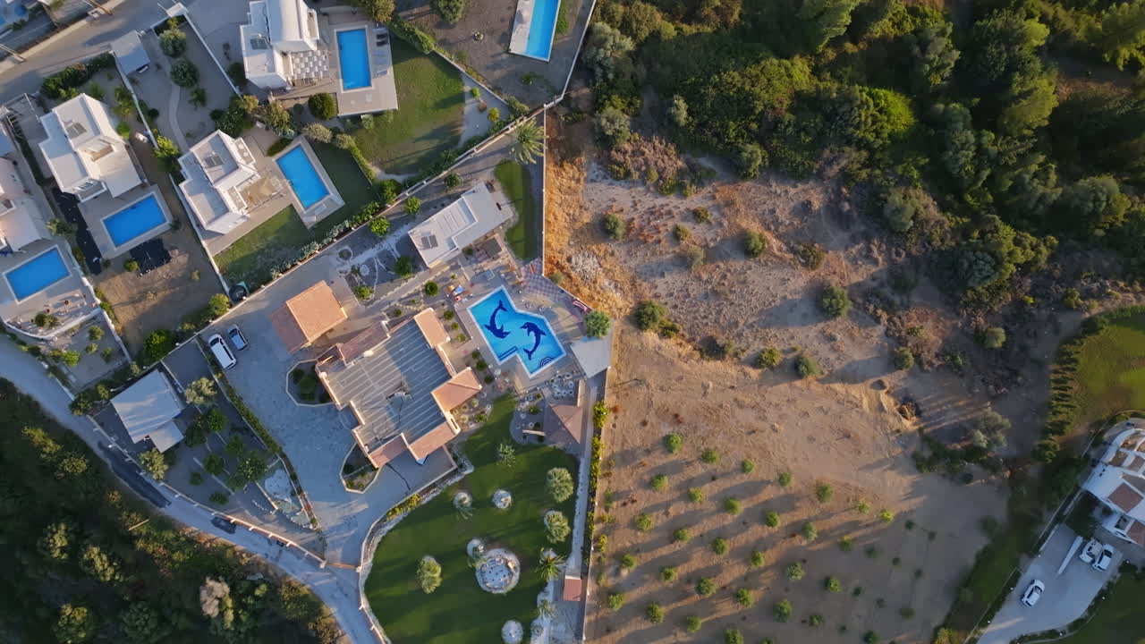 Screwdriver drone shot rising above a pool, at a villa in Greece, sunny morning