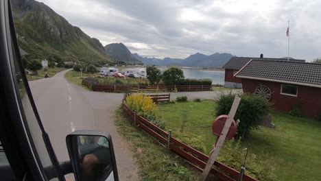 wide shot from the window of a campervan driving through the fjords of lofoten, norway coming into ramberg and rambergstranda with houses next to the ocean