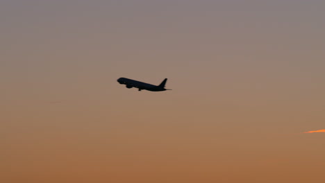 black silhouette of plane flying in evening sky