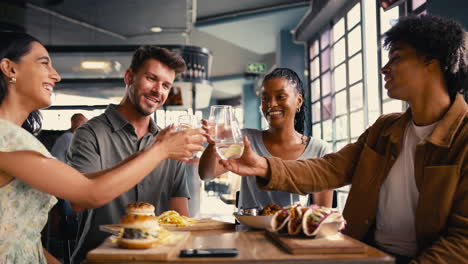 group of friends meeting up in restaurant doing cheers with water