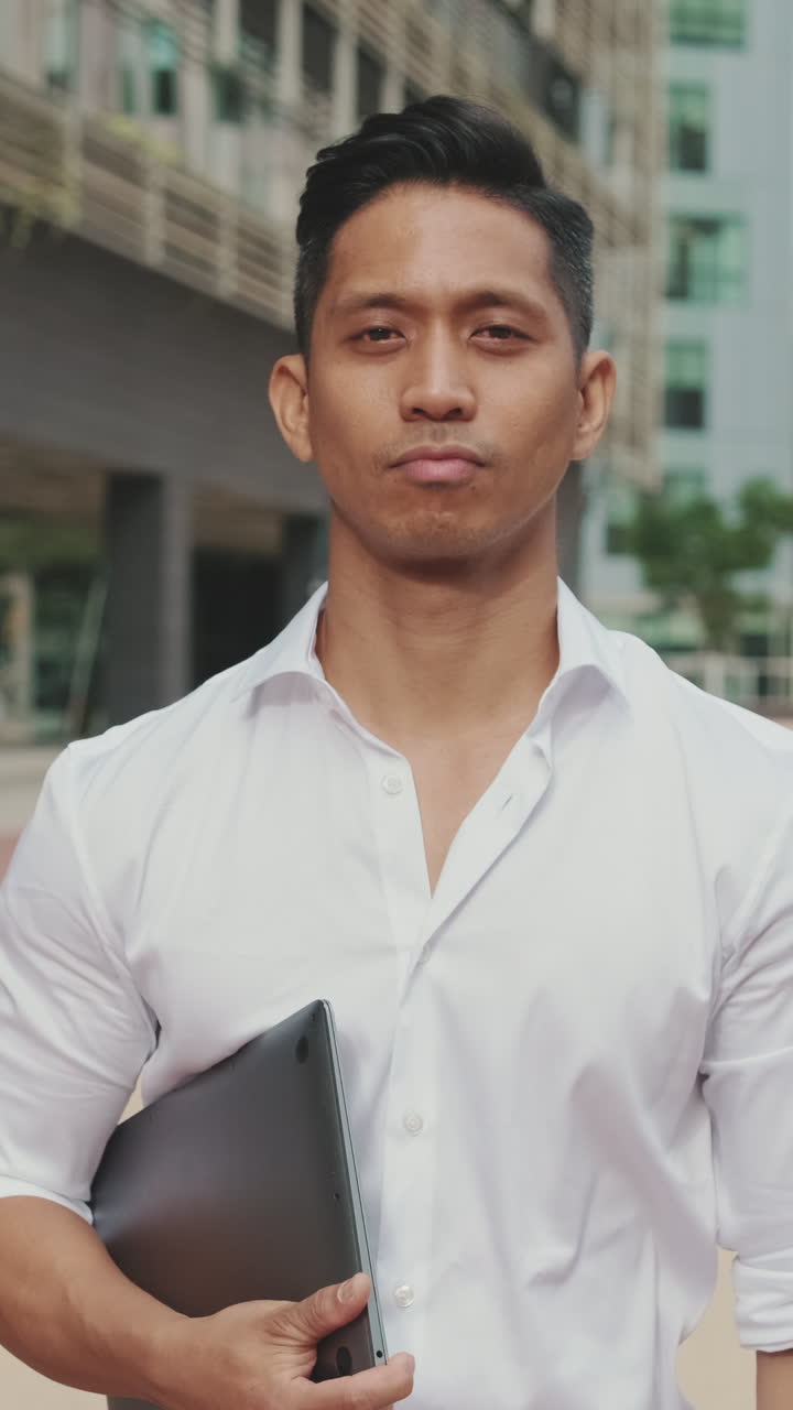 Portrait of a man in a white shirt holding a laptop