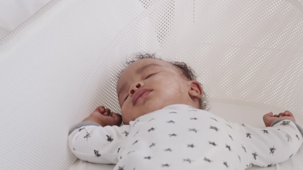 Close up of newborn baby sleeping in a crib, waist up