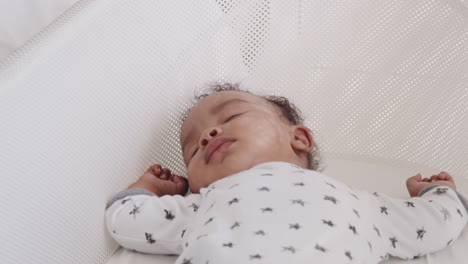 Close-up-of-newborn-baby-sleeping-in-a-crib,-waist-up