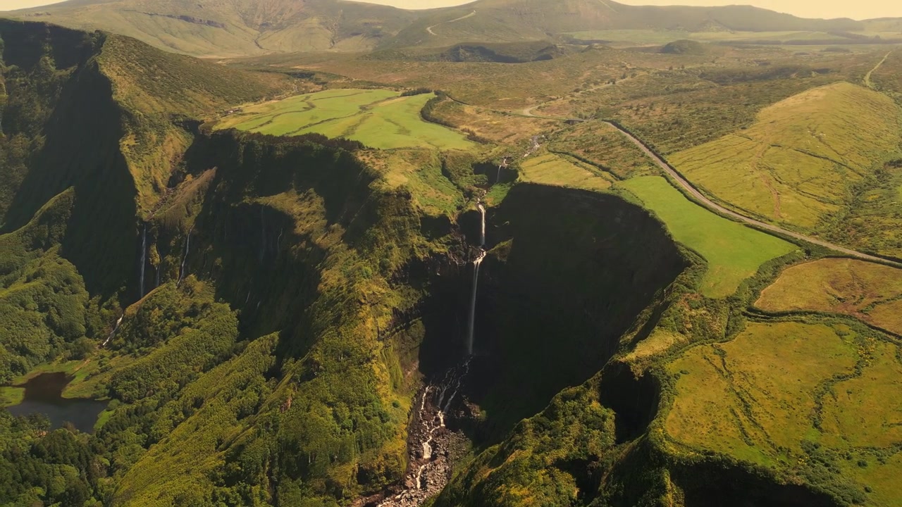 Vista aerea di scogliere spettacolari e cascata che sfocia in una lussureggiante valle verde a Flores.