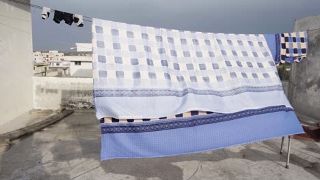 a vibrant bed sheet on wire at roof to dry in the sun