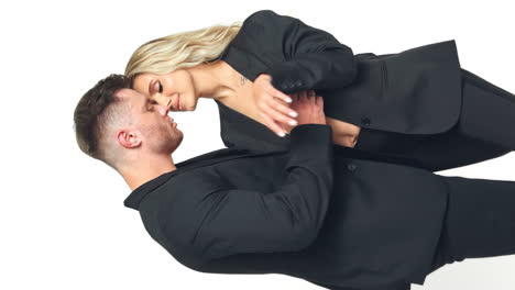 sportive man caressing blonde woman. caucasian couple kissing and stroking each other. vertical screen. white backdrop.