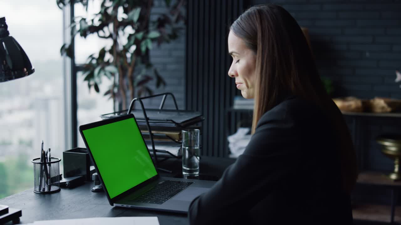 mujer de negocios llamando video en una computadora portátil con pantalla verde en la oficina