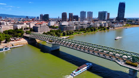 Motor boat goes under the Old Bridge by the Danube River. Aerial perspective on Bratislava, Slovakia.