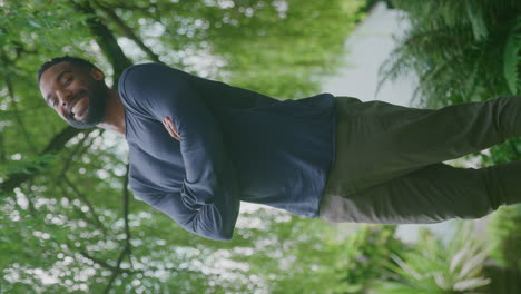 vertical video portrait of relaxed smiling man standing in garden at home after retirement