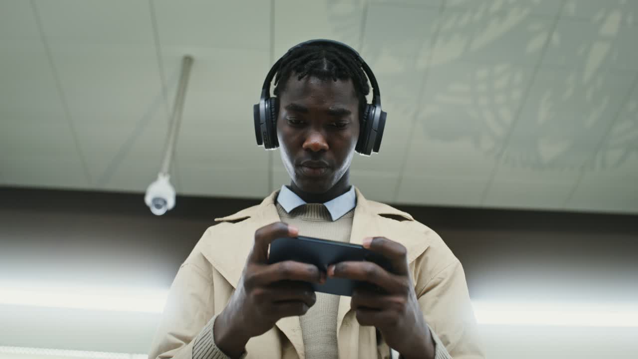 Man playing games on his phone with headphones on