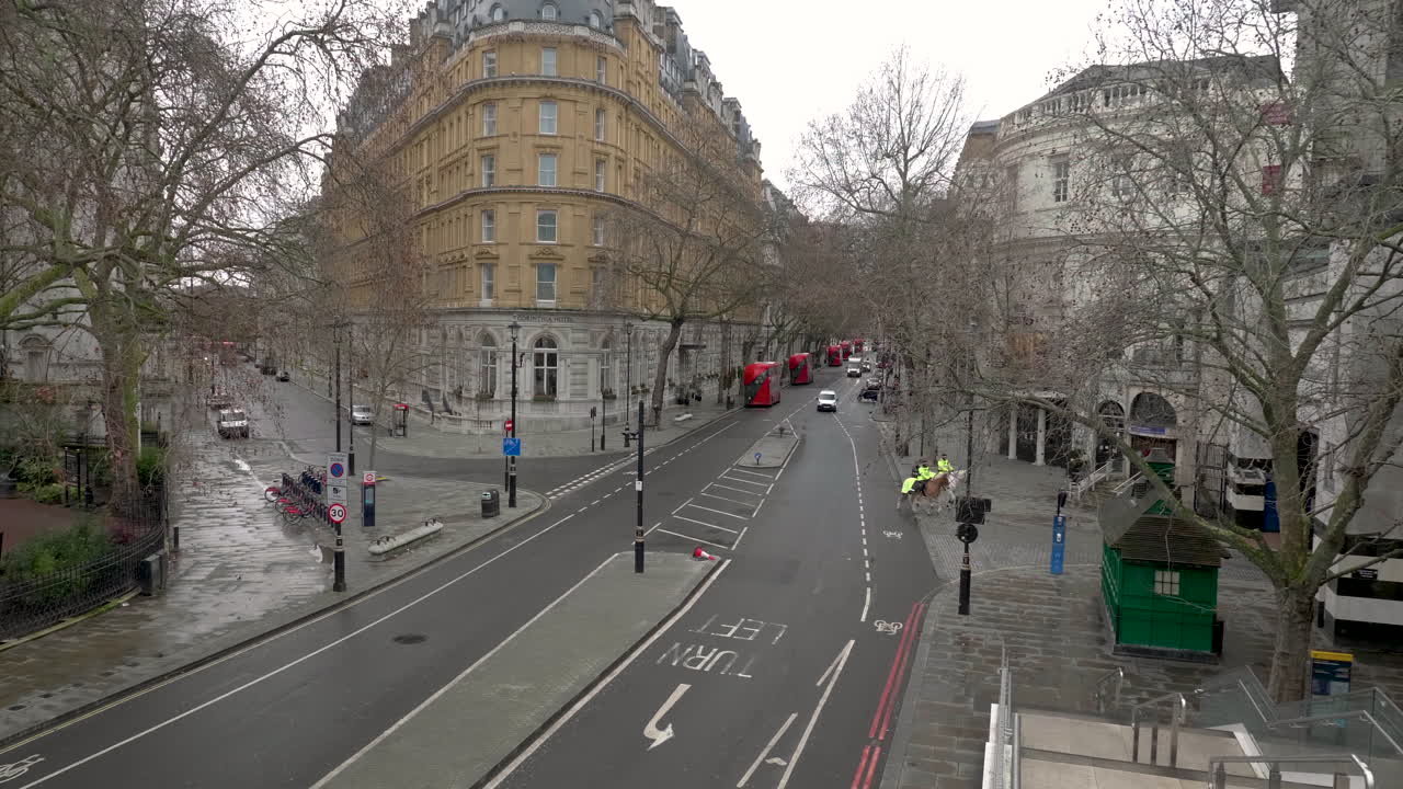 toma estática de la policía montada cruzando lentamente la famosa y vacía avenida northumberland, londres