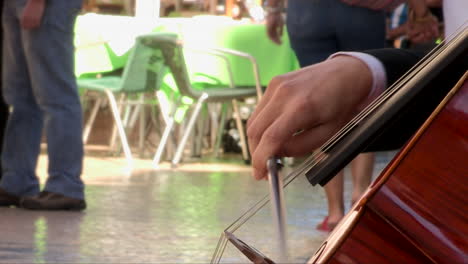 street musician, young man playing cello on augusta street in lisbon, close-up of cello hand and bow with passersby