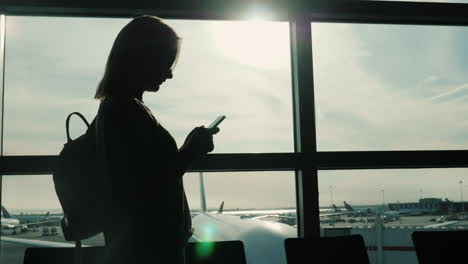 Silhouette-Frau-Mit-Smartphone-Im-Flughafen